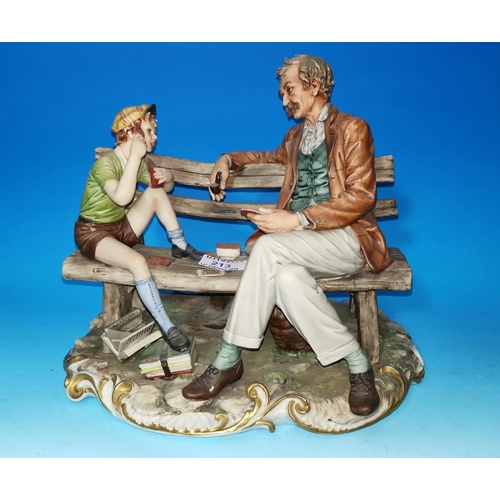 213 - A Capodimonte group: man and boy playing cards on a bench, length 12