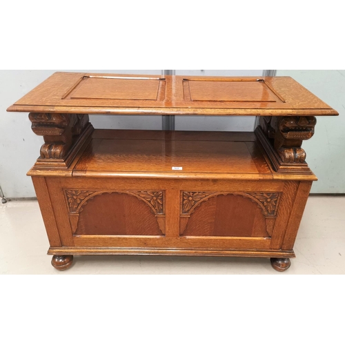 633 - An early 20th century golden oak monks bench with lion arm rests and box seat