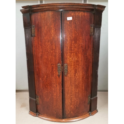 597 - A Georgian oak bow front corner cupboard with moulded cornice and reeded side pillars, enclosed by 2... 