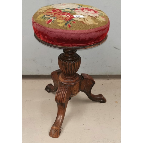 636 - A Victorian circular revolving walnut piano stool with needlework seat