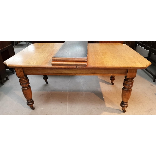 603 - A Victorian golden oak wind out dining table, rectangular canted top with 2 spare leaves, on turned ... 