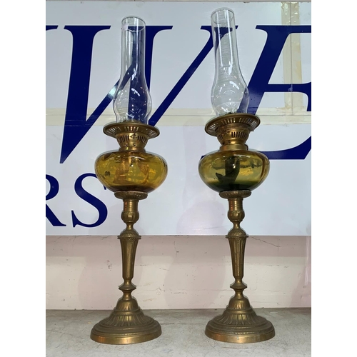 463 - A pair of brass column oil lamps with amber glass reservoirs and chimneys