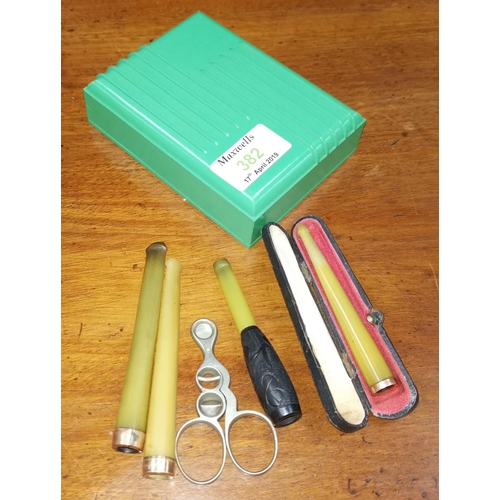 382 - Three gold tipped cigarette holders, cigar scissors and green Bakelite box