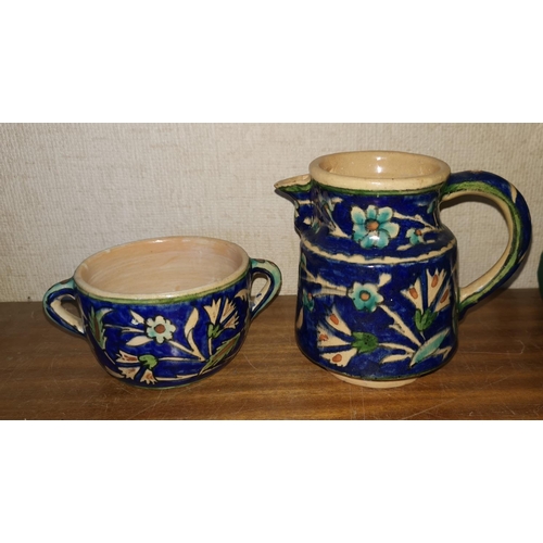 283 - A Persian jug decorated with blue flowers and glazed and a matching two handled cup