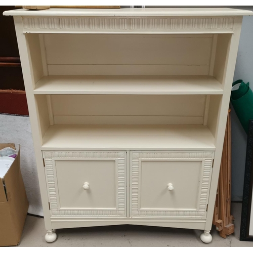 549 - A 1930's white painted bookcase with 2 shelves over double cupboard, on bun feet