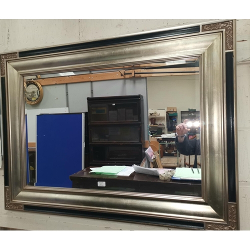 577 - A large bevelled edge wall mirror in reproduction classical style silver and black frame, 34