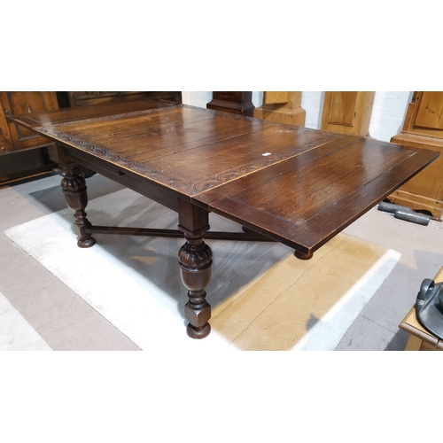 593 - A 1920's Jacobean style large oak table, draw leaf with carved lunette border, on cross stretchers, ... 