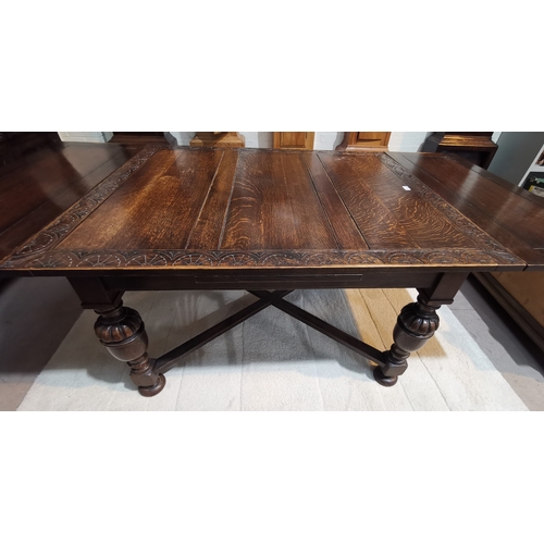 593 - A 1920's Jacobean style large oak table, draw leaf with carved lunette border, on cross stretchers, ... 