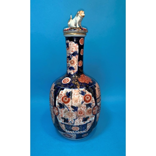 242 - A 19th century Japanese Imari bottle vase with fluted lower section and cover surmounted by a dog of... 