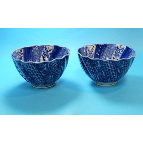 227 - A Chinese / Japanese pair of rice bowls of spiral fluted form, decorated with alternating blue and w... 