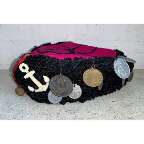 453 - A WWII period astrakhan hat with red felt centre, attached coins, recovered in Belgium 1945