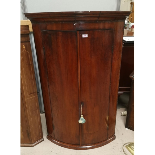 584 - A Georgian mahogany bow front corner cupboard enclosed by 2 doors
