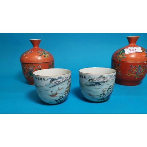 281 - A pairof Chinese covered jars with reversable cup / covers decorated in polychrome against an orange... 