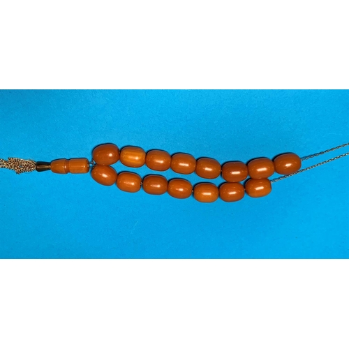 309 - A necklace of butterscotch coloured beads on metal chain, 15 oval shaped beads, 50 gm gross, 15mm