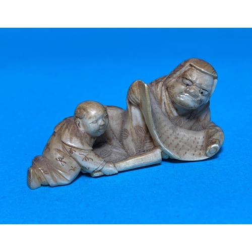 460 - A Meiji period netsuke depicting a man with scroll and child, length 6cm