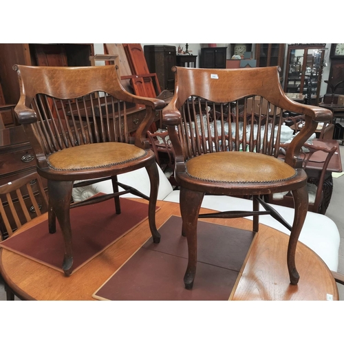 540 - A pair of early 20th century oak stick back smokers bow arm chairs with studded tan coloured seats o... 