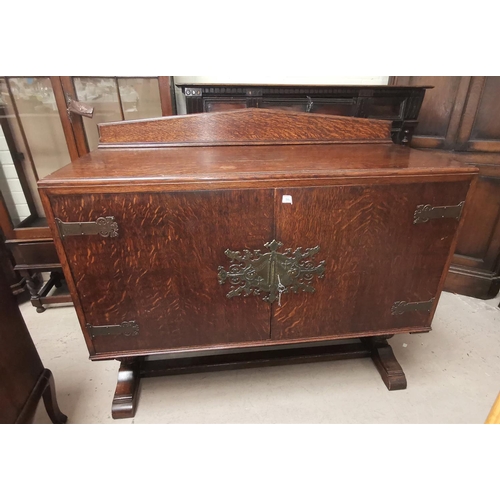 588 - A 1930's oak sideboard with ornate brass hinges, 2 doors enclosing cellaret and drawers, on carved b... 