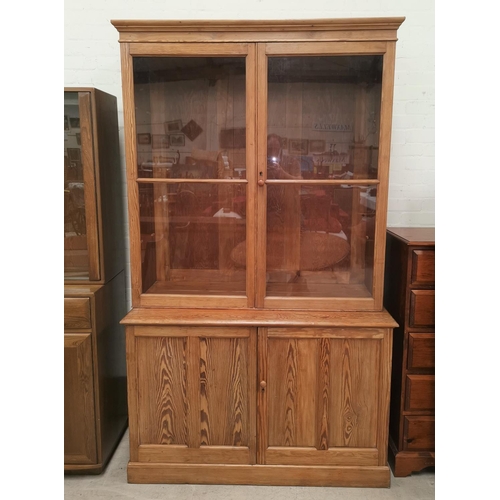 631 - A Victorian pitch pine full height bookcase with 2 glazed door over double cupboard, on plinth base