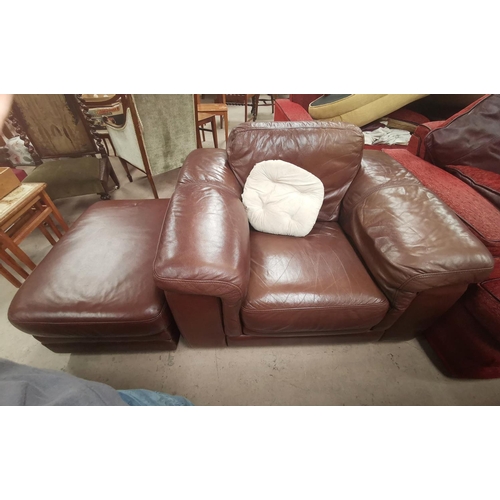 634 - A large club style armchair and pouffe in brown leather
