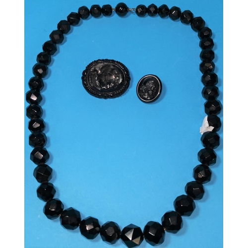 305 - A Whitby jet necklace of faceted beads, a brooch decorated with flowers and a cameo brooch