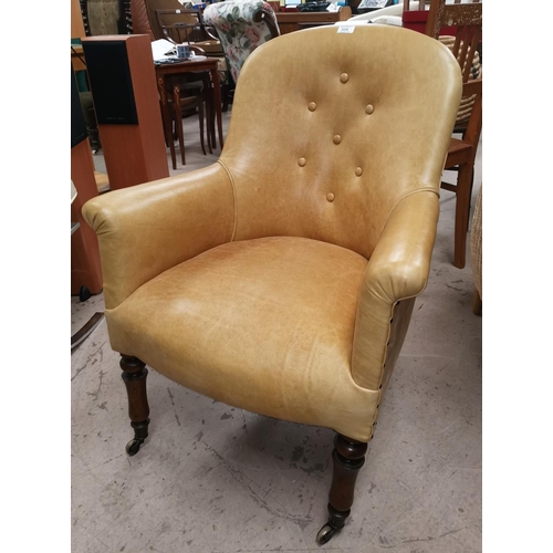 539 - A Victorian tub shaped armchair in mustard buttoned leather, on turned legs and castors