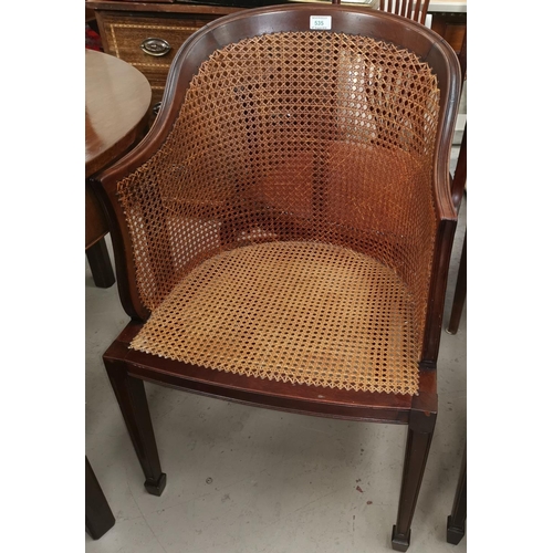 535 - An early 20th century mahogany tub shaped armchair with woven cane seat and back
