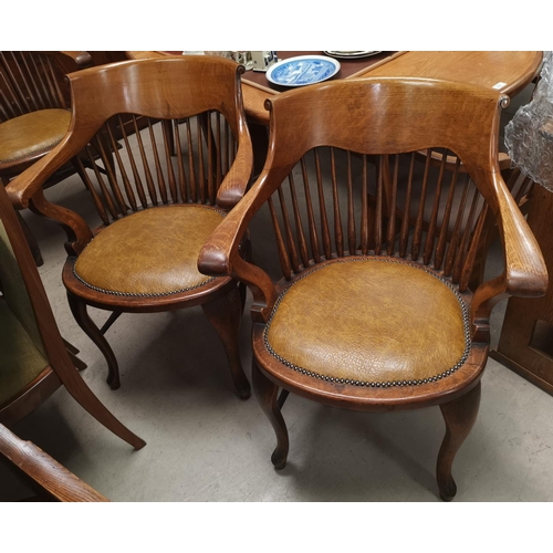 542 - A pair of early 20th century oak stick back smokers bow arm chairs with studded tan coloured seats o... 
