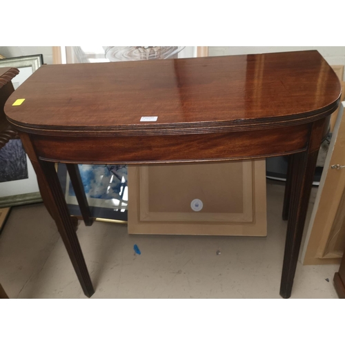 650 - A Georgian mahogany fold over tea table on tapering reeded legs
