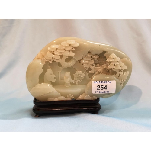 254 - A jade coloured hardstone carving depicting figures and trees in front of a cave, length 7