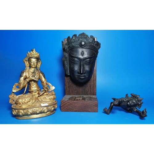 173a - A gilt metal figure of seated Buddha; a similar smaller bronze figure and a bronzed face of Buddha, ... 