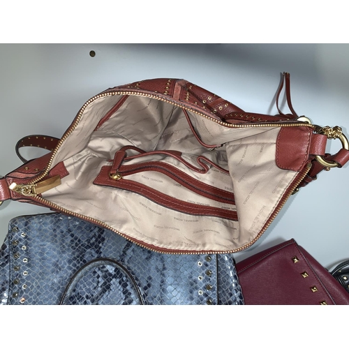 715 - A Michael Kors labelled maroon cross body gilt studded purse; a Michael Kors labelled Selma handbag ... 
