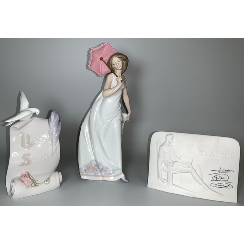 20 - A Lladro figure of a girl in long white dress with pink parasol; a Lladro Society plaque and another... 