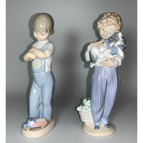 22 - 2 Lladro figures - boy holding a spaniel and boy with dice and toy truck (small firing crack to dog ... 