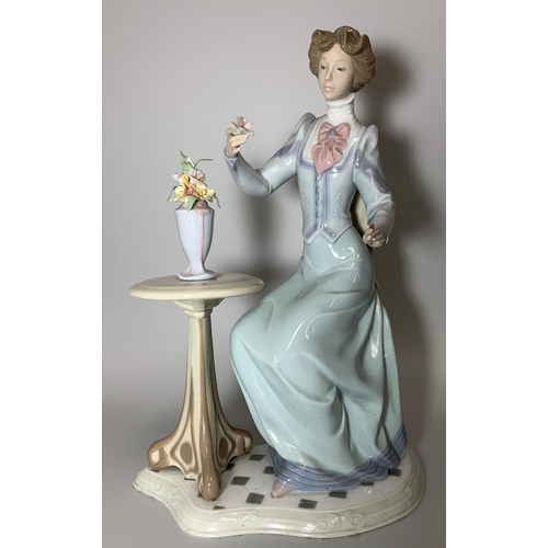 25 - A large Lladro figure, an Edwardian lady seated by a table with vase of flowers, ht 34cm