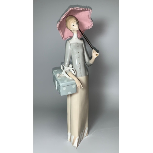 26 - A Lladro figure of a lady with parasol holding a gift parcel