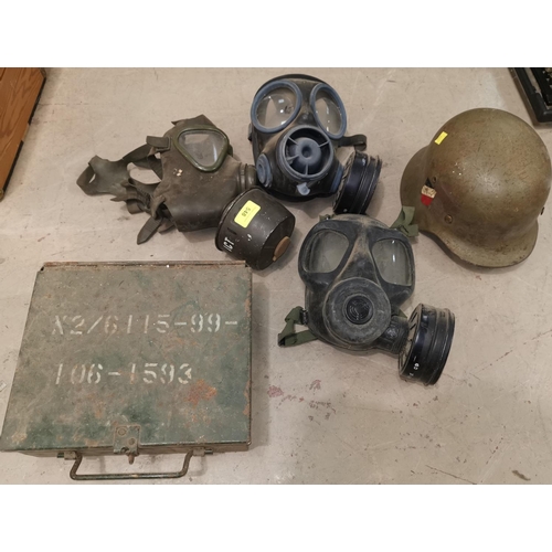 548 - 3 military gas masks; a military ammunition box; a WWII German helmet