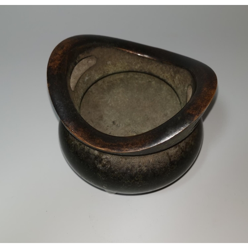 125 - A Chinese patinated bronze incense burner of squat tripod form, flattened loop handles, 12 cm