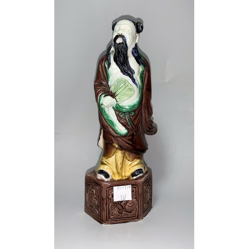 137 - A Chinese porcelain brown/green glazed figure of a man with lotus leaf fan, height 22 cm