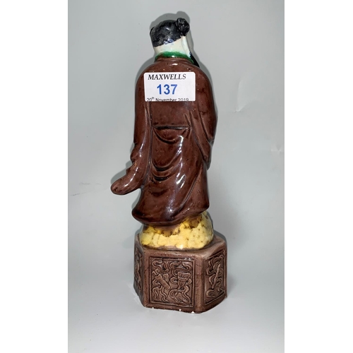 137 - A Chinese porcelain brown/green glazed figure of a man with lotus leaf fan, height 22 cm