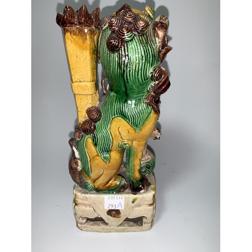 293a - A Chinese 'Kangxi' dog of Fo in green/yellow/brown with revolving ball to lower leg, height 21 cm