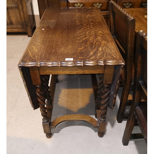 608 - A 1930's golden oak drop leaf dining table, canted and scalloped on barley twist gate legs