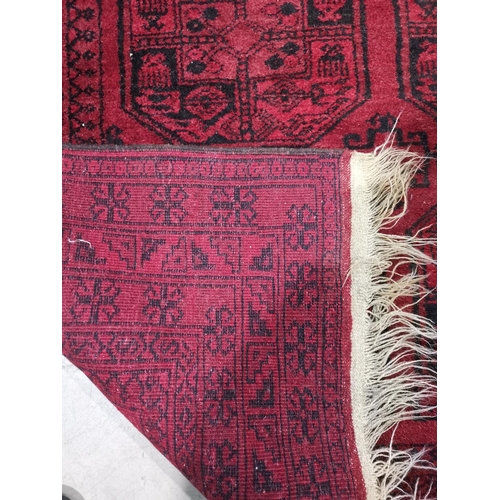 645 - An Afghan rug with repeat octagonal pattern on red ground, 200 x 136 cm