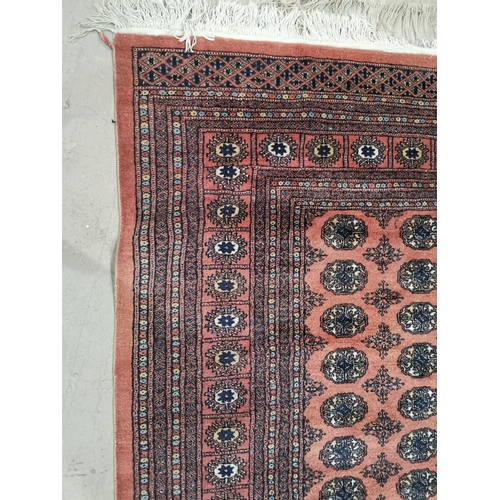 647 - A Pakistan Bokhara rug with elephant foot motif repeated on a dusky pink ground, 250 x 195 cm