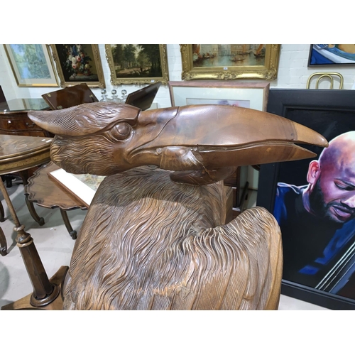 488 - A large carved wood sculpture depicting a pelican with a fish in its beak, height 128 cm