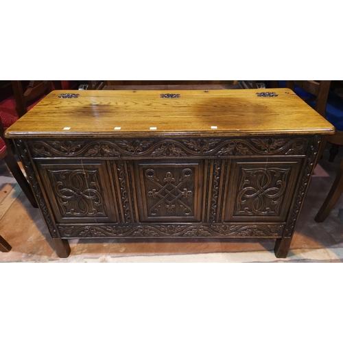 681 - A golden oak blanket box carved in the Jacobean style, with hinged lid and panelled front