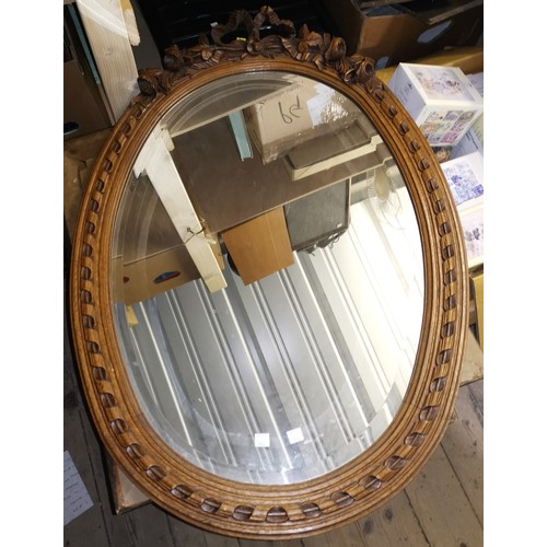 660 - A French bevelled glass mirror in oval carved oak frame, with flower and ribbon finial, 89 cm overal... 