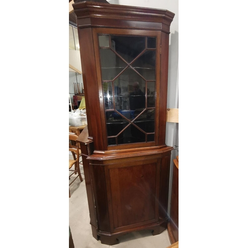 561A - A 19th century mahogany corner cupboard with glazed upper section and panelled base