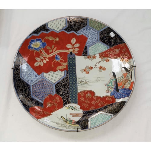 101a - A large Japanese Imari porcelain saucer dish, decorated with 2 figures on a scroll laid over a panel... 