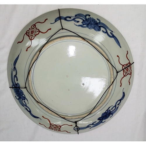 101a - A large Japanese Imari porcelain saucer dish, decorated with 2 figures on a scroll laid over a panel... 