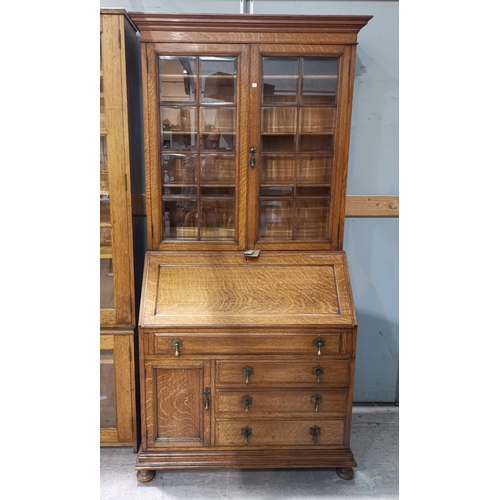 630 - An early 20th century golden oak bureau/bookcase with bevelled glass doors, fall front, 4 drawers an... 
